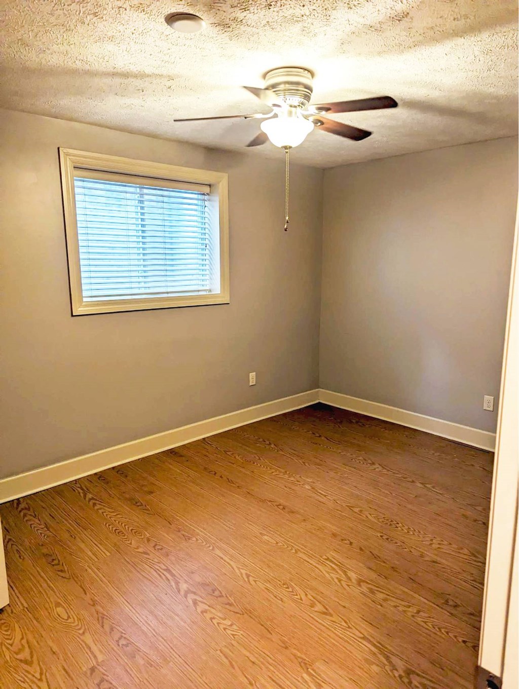 A room with a ceiling fan and a window with blinds.
