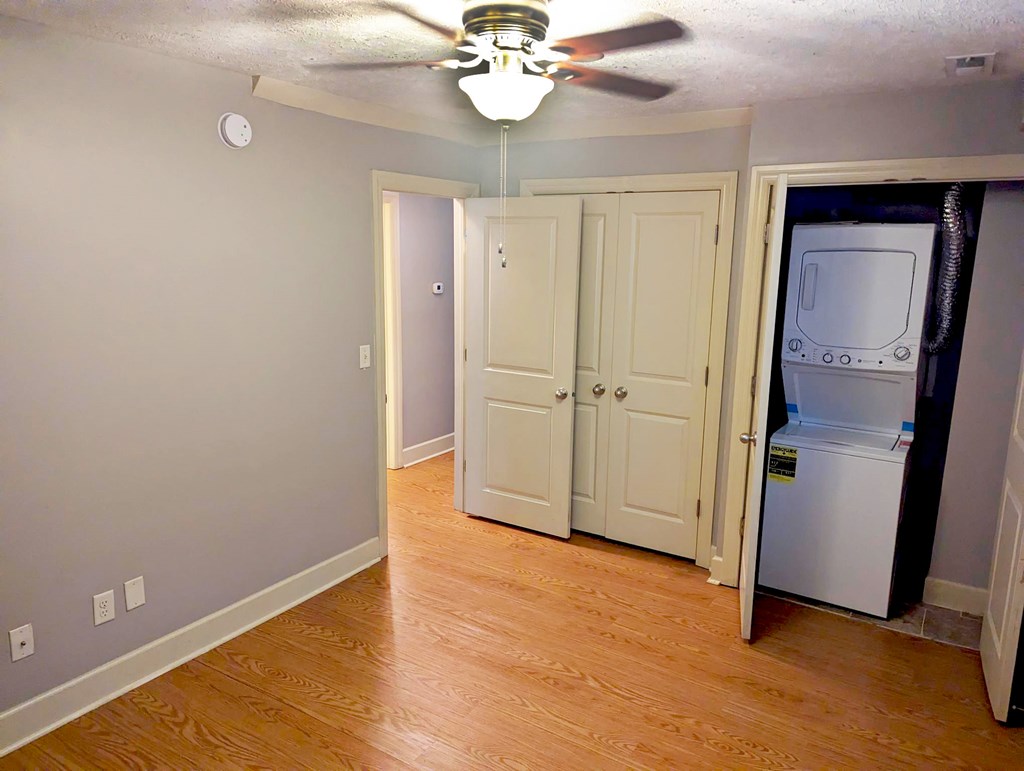 A room with a ceiling fan and a refrigerator in it.
