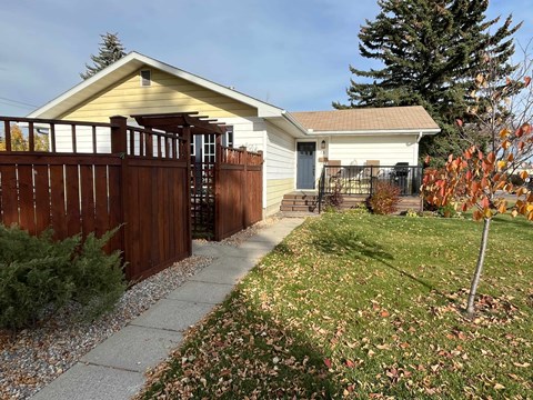 A house with a brown fence and a tree with orange leaves.