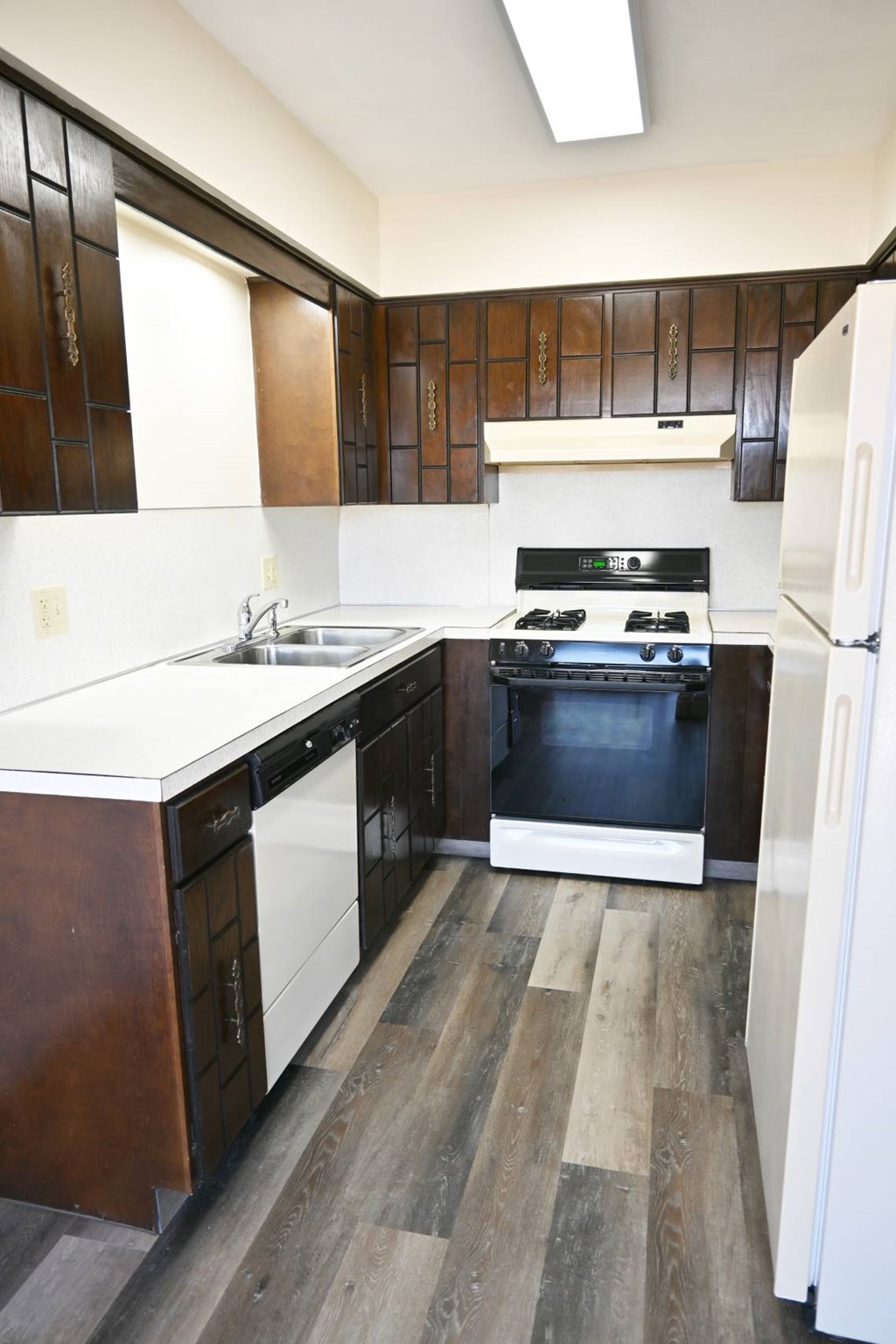 A kitchen with a white fridge and a white sink.