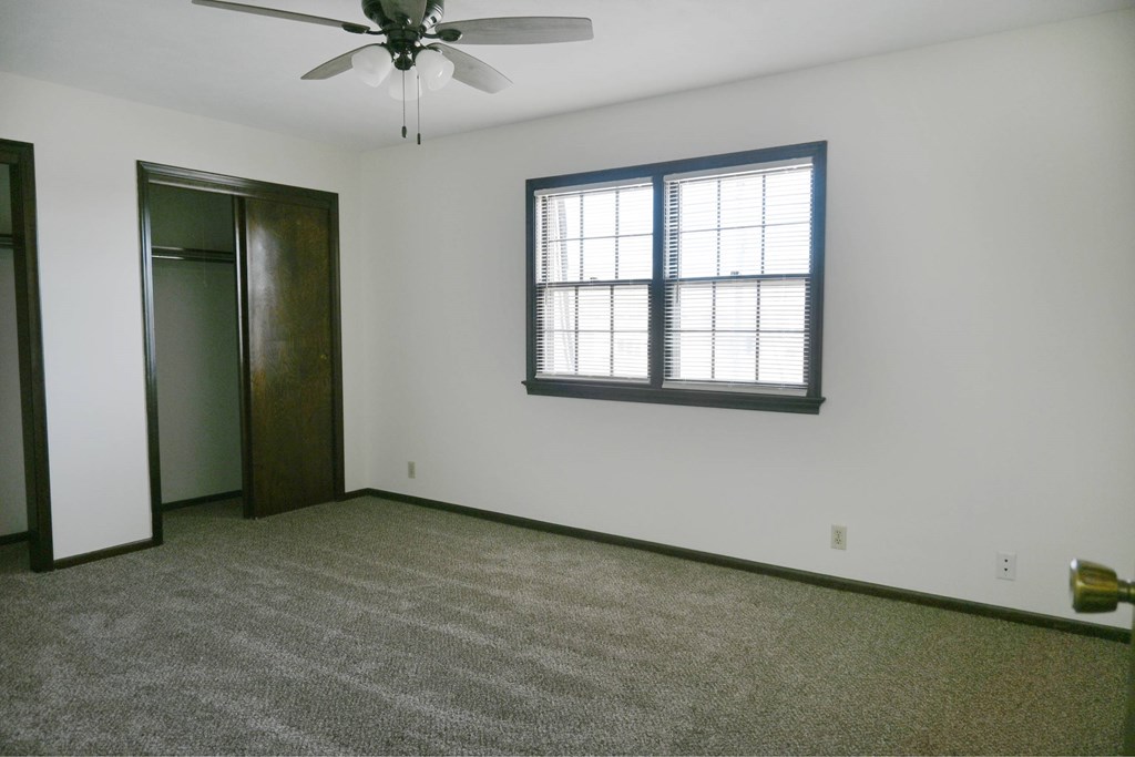 A room with a ceiling fan and a window with blinds.