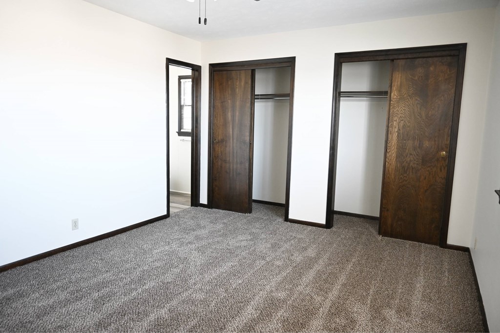 A room with carpeted floor and three doors.