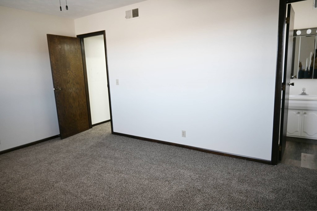 A room with a carpeted floor and a wooden door.