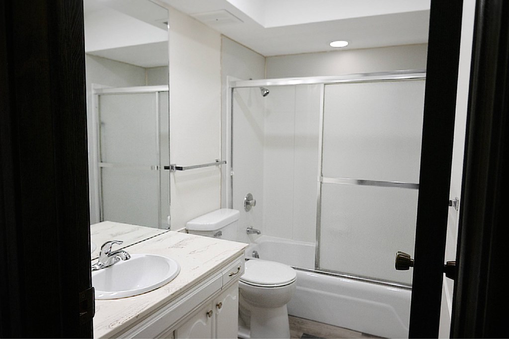 A white bathroom with a toilet, sink, and shower.