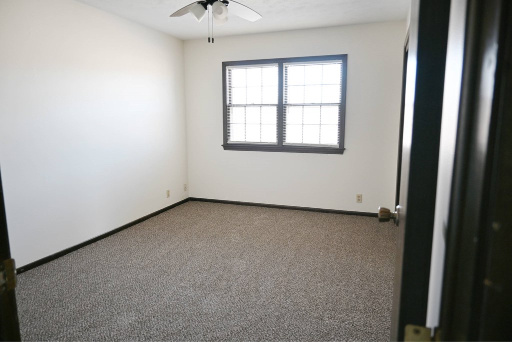 A room with a ceiling fan and a window.