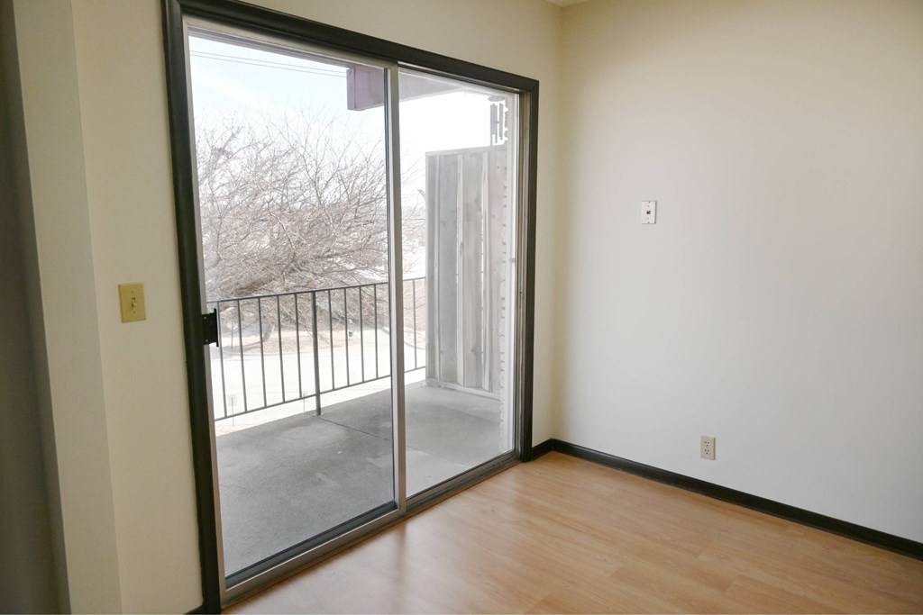 A room with a sliding glass door leading to a balcony.