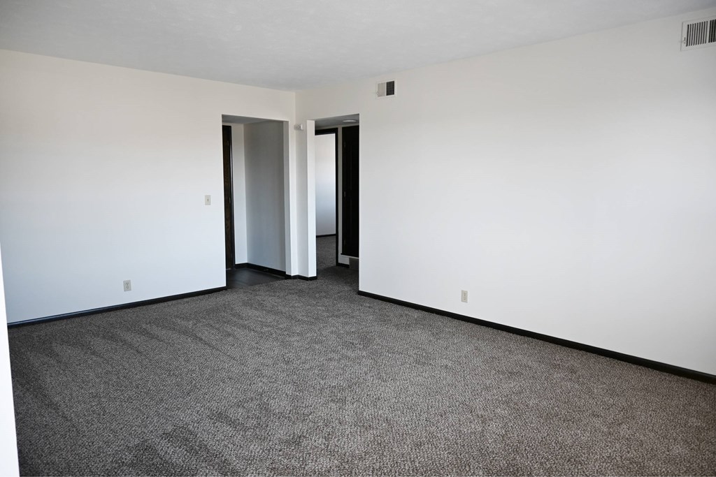 A room with a carpeted floor and two doors.