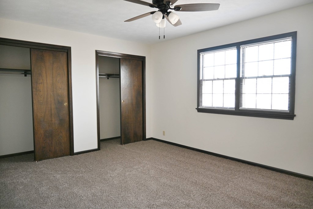 A room with a ceiling fan and a window with blinds.