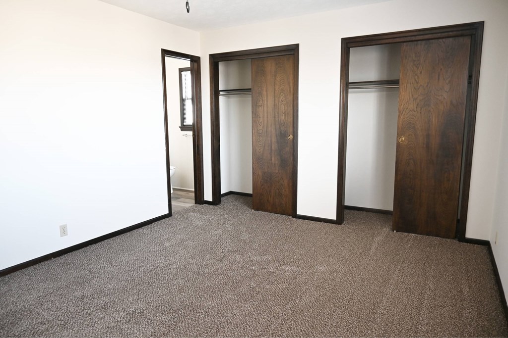 Three brown doors in a white room.
