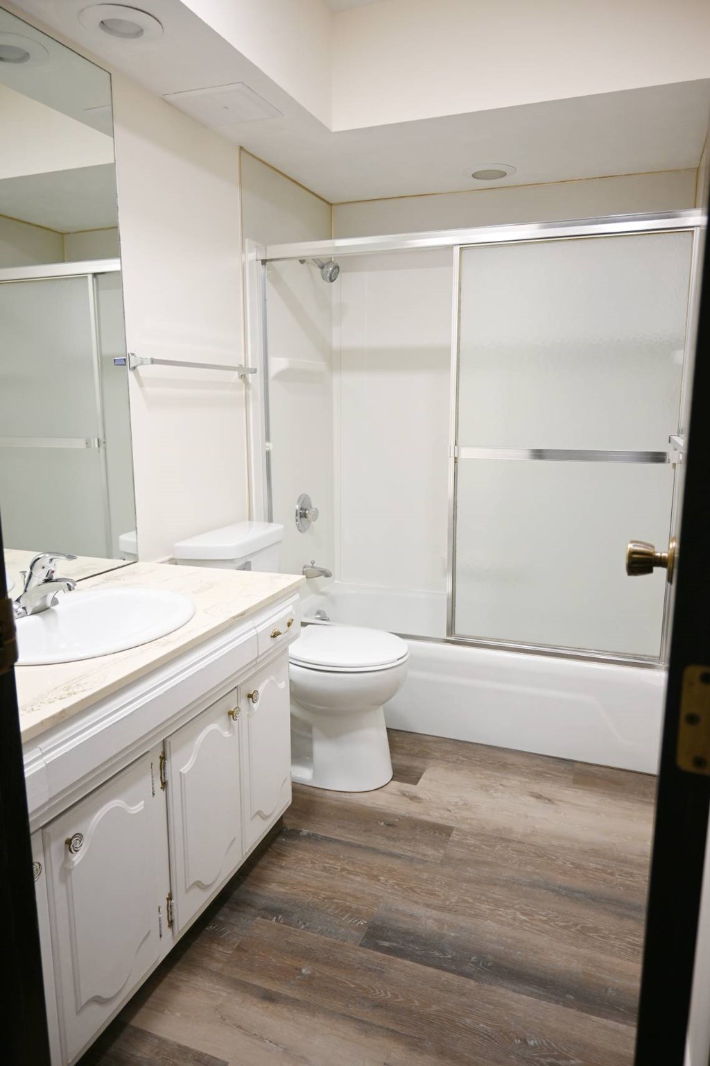 A white toilet sits in a bathroom next to a sink and a bathtub.
