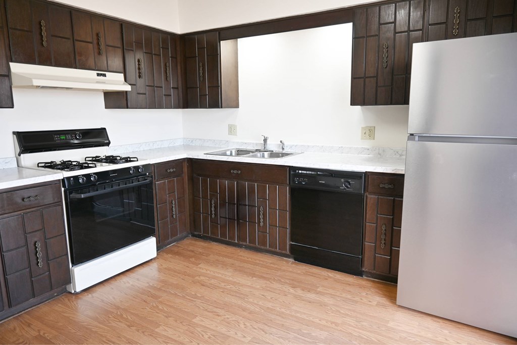 A kitchen with a white fridge, black oven and wooden cabinets.