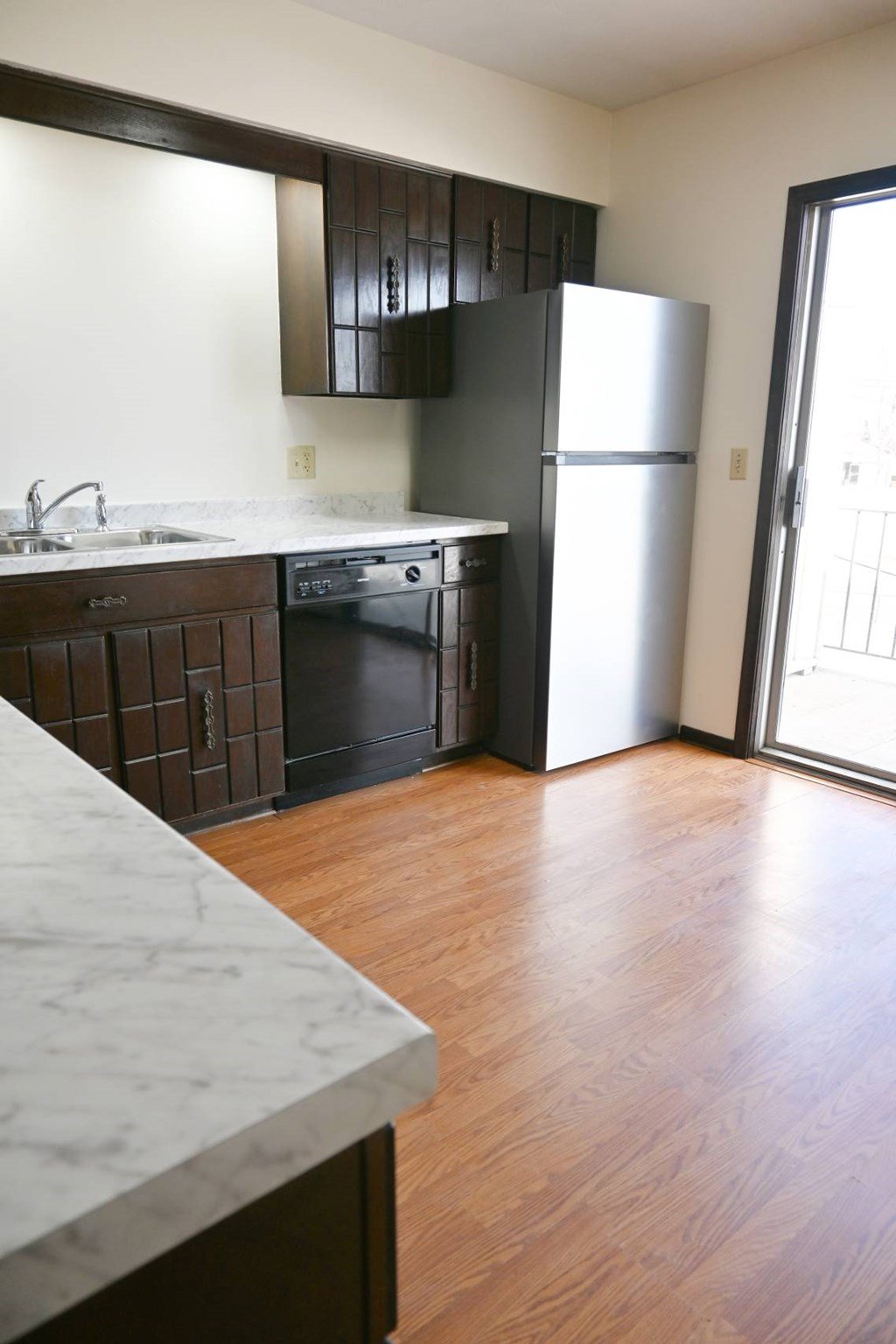 A kitchen with a marble counter top and a refrigerator.