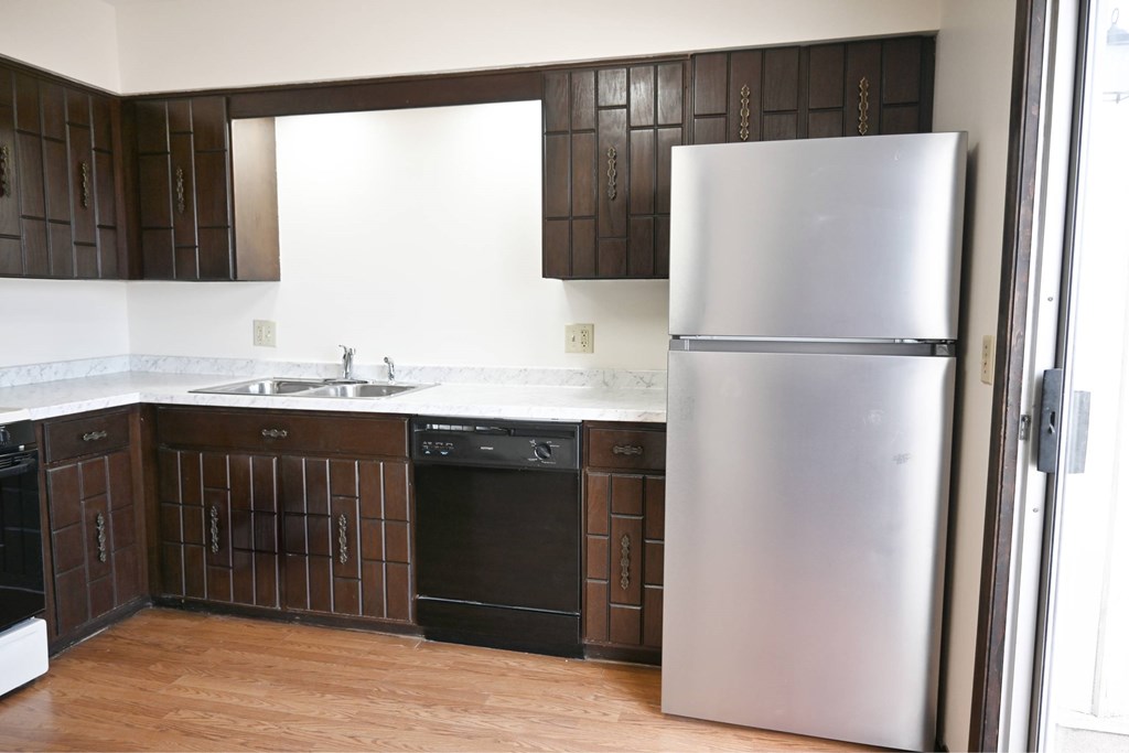 A kitchen with a refrigerator, oven, and sink.