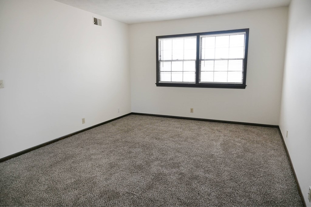 A room with a carpeted floor and a window.