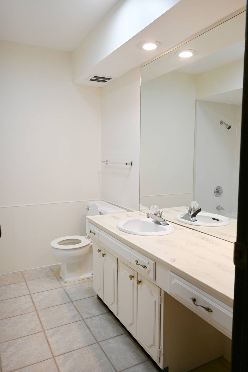 A white bathroom with a toilet, sink and mirror.