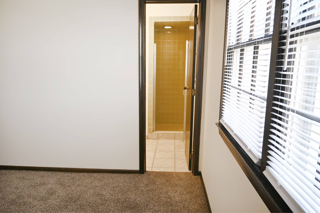 A hallway with a carpeted floor and a doorway leading to another room.