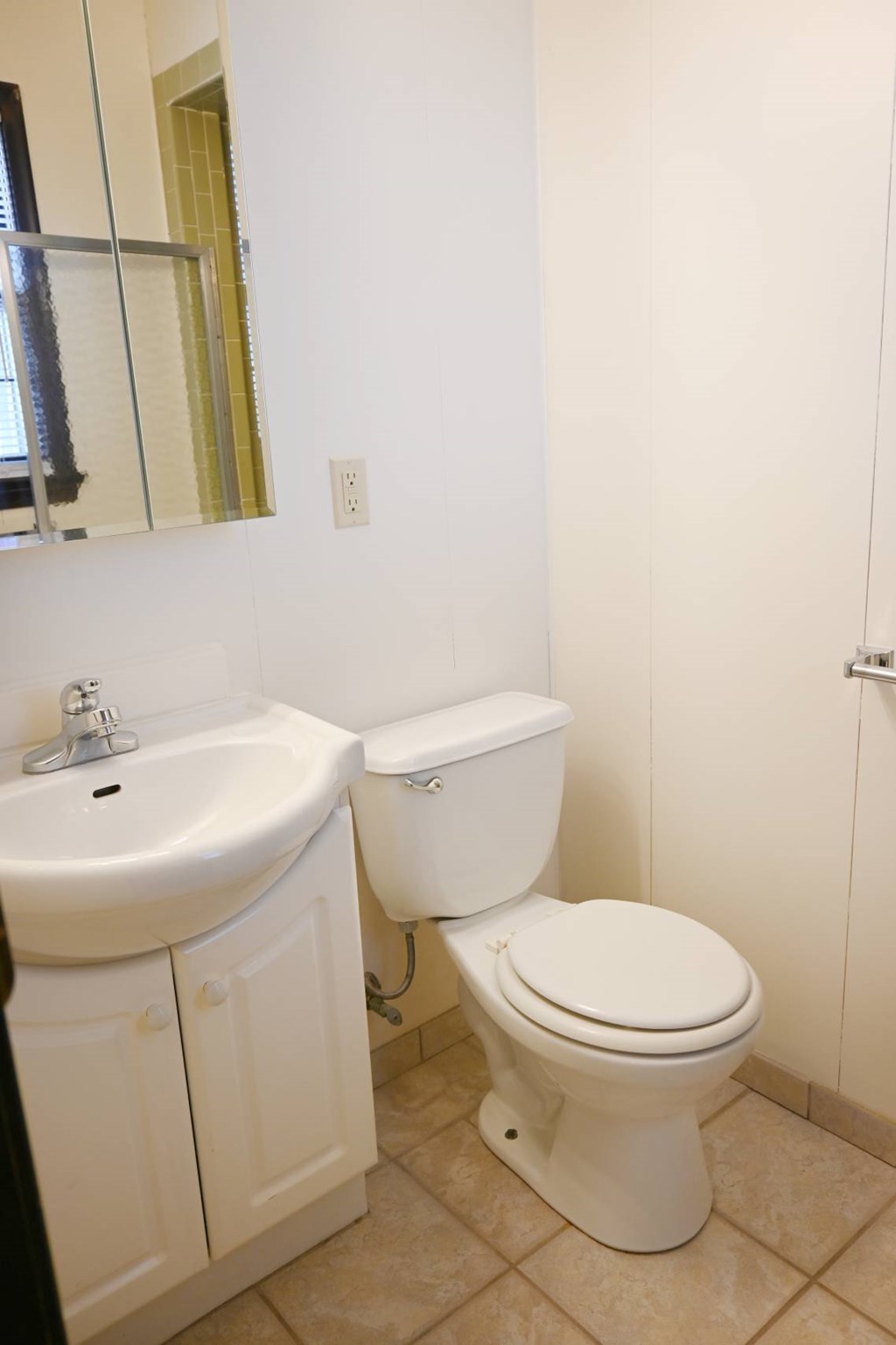 A white toilet sits next to a sink in a bathroom.