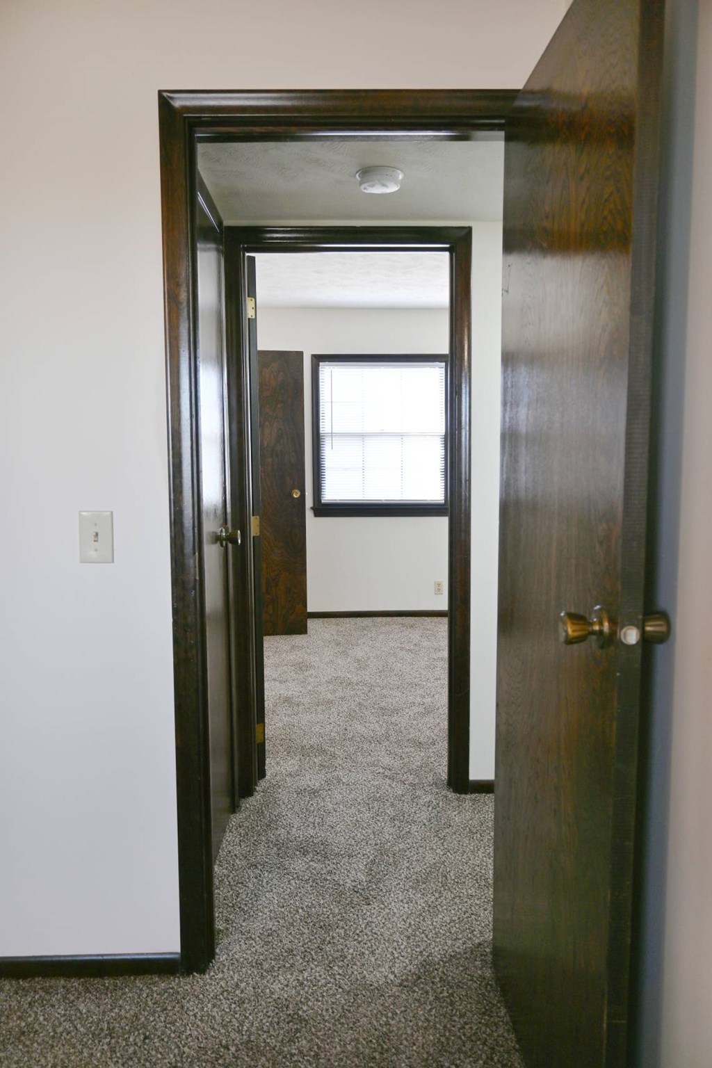 A hallway with a door on the left and a window on the right.