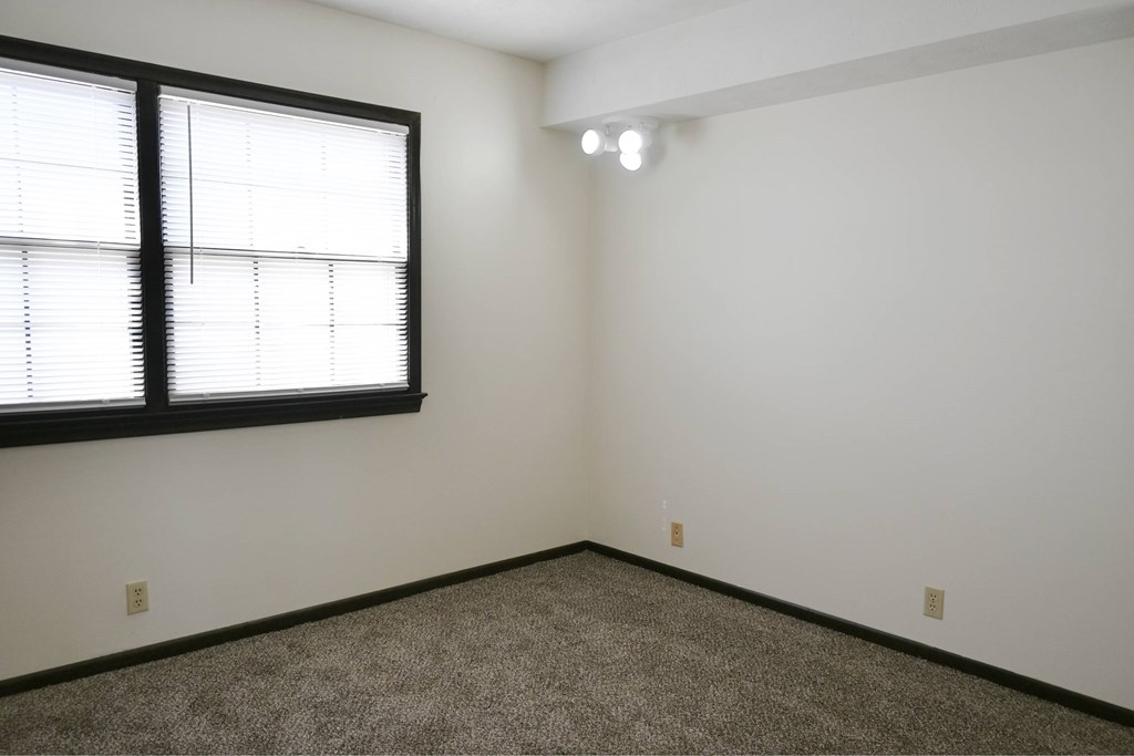 A room with a window and carpeted floor.