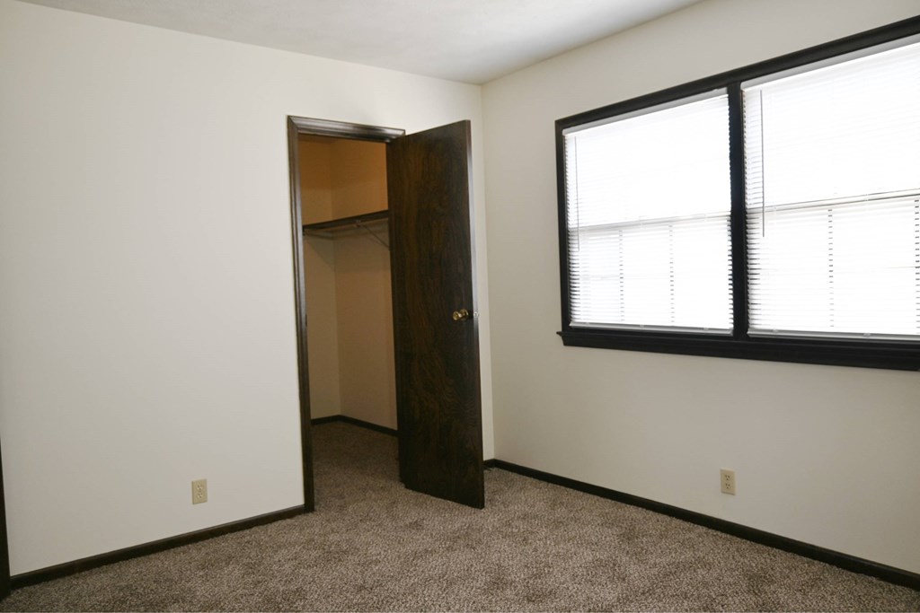 A room with a brown door and a window with blinds.