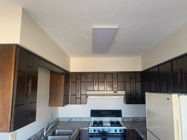 A kitchen with black cabinets and a white stove top oven.