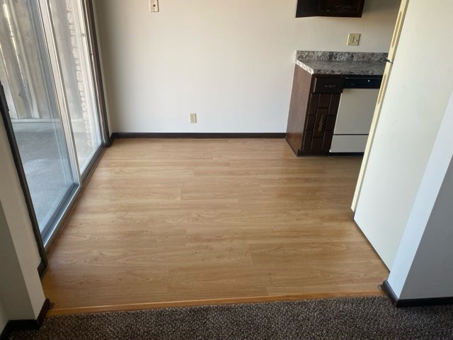 A kitchen area with a white wall and a wooden floor.