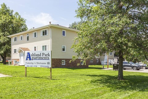 A sign for Ashland Park Apartments is in front of a two-story building.