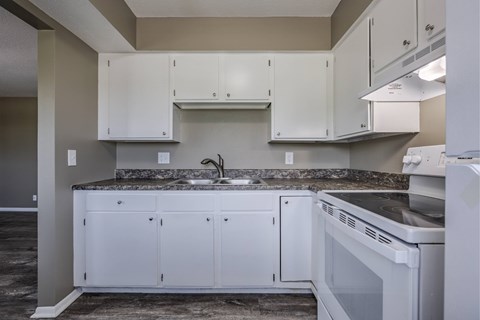A kitchen with white cabinets and a granite countertop.