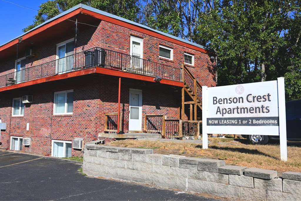 A red brick building with a sign that says Benson Crest Apartments.