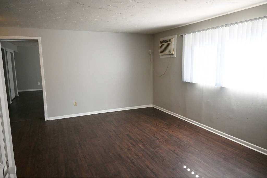 A room with wooden floors and a window with curtains.