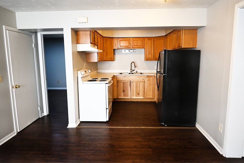 A kitchen with wooden cabinets and a black refrigerator.