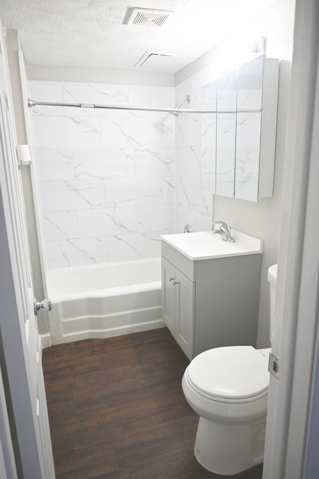 A white toilet in a bathroom with a marble wall.