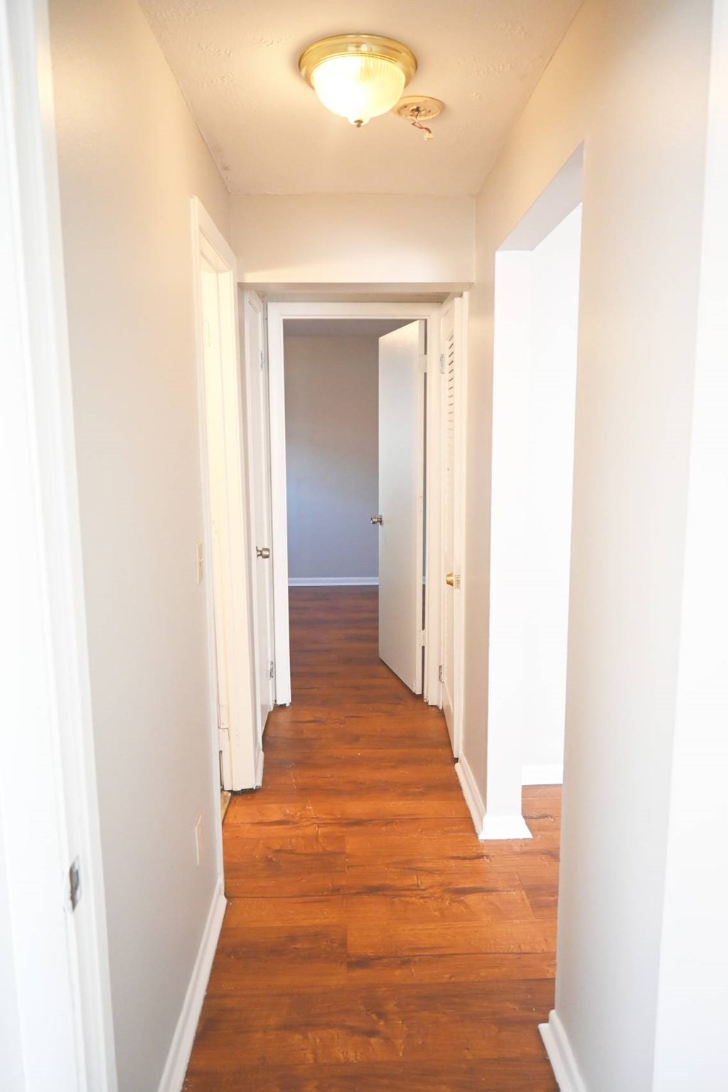 A long hallway with white walls and wood floors.