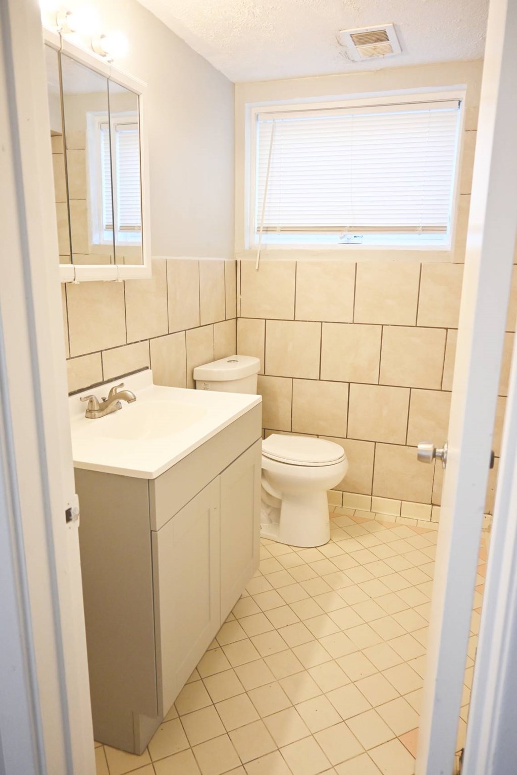 A white toilet sits in a bathroom with a sink and a mirror.