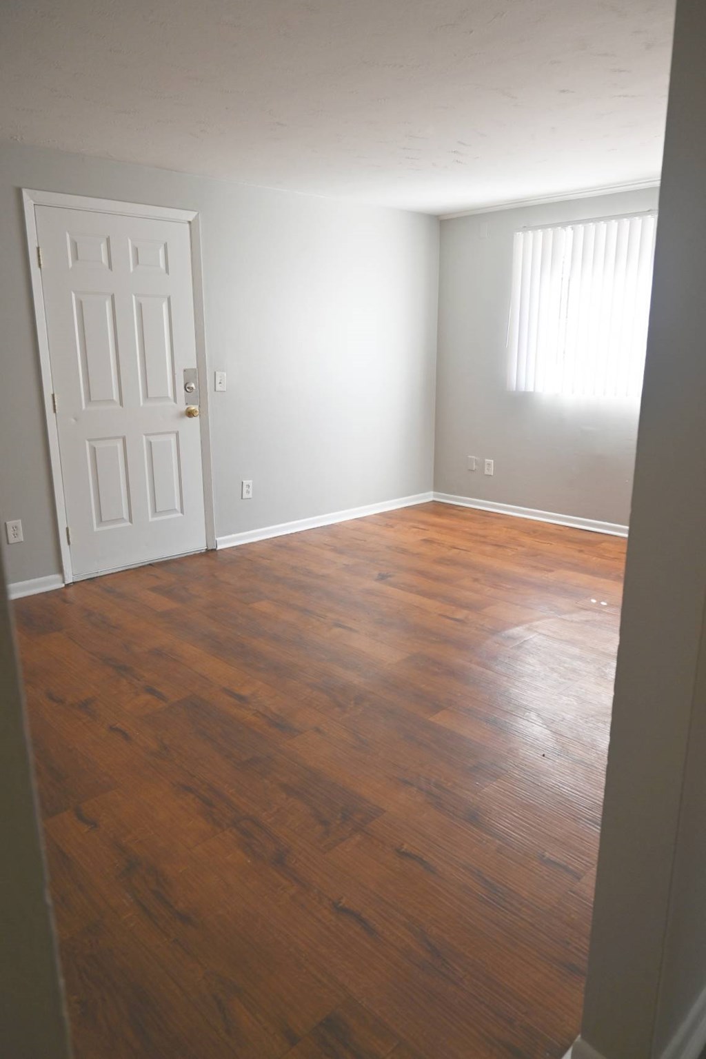 A room with a white door and wooden flooring.