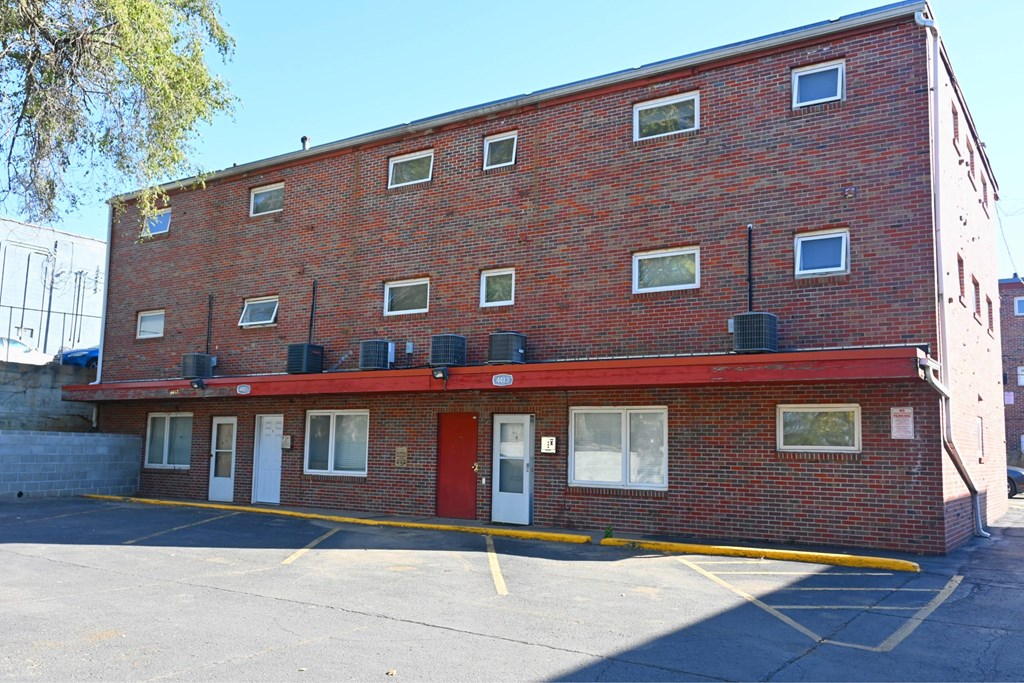 A red brick building with a parking lot in front.
