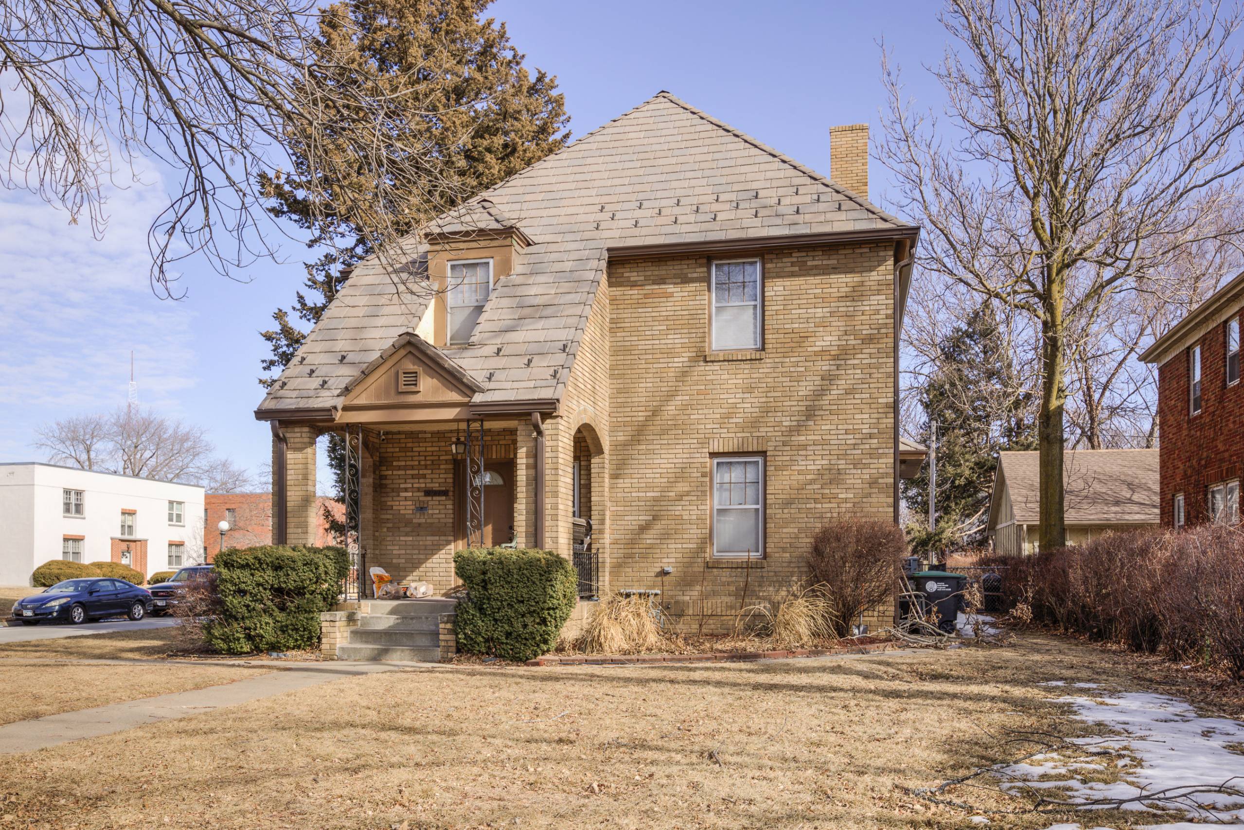 A house with a brown brick exterior and a white car parked in front.