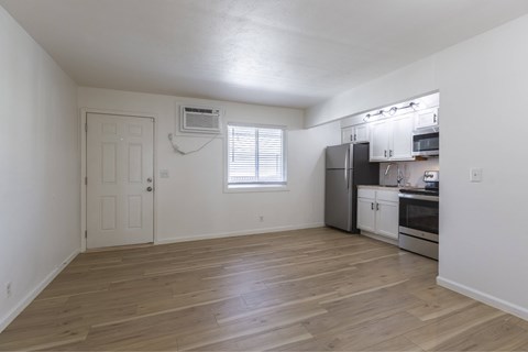 A kitchen with white cabinets and a wooden floor.