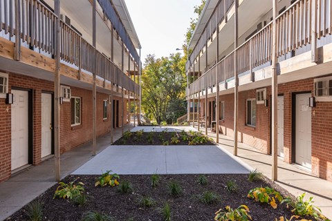 A long, narrow courtyard between two rows of red brick buildings with white doors.