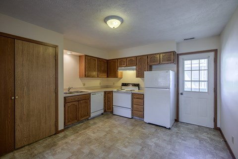 A kitchen with white appliances and wooden cabinets.
