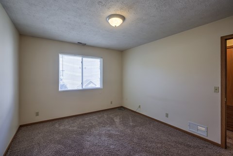 A room with a window and carpeted floor.