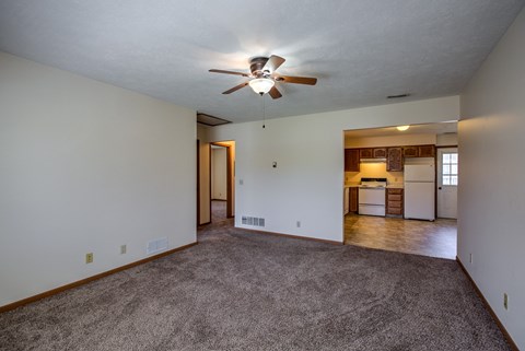 A room with a ceiling fan and carpeted floor.