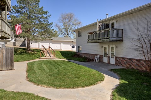 A small American flag hangs from a tree in a grassy area.
