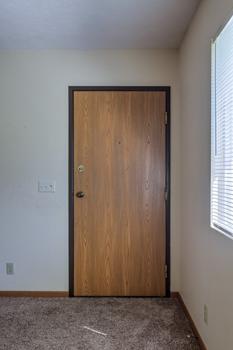 A brown wooden door is closed and has a handle and a lock.
