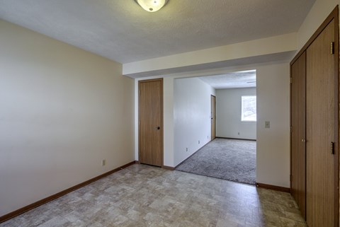 A room with a carpeted floor and two doors.