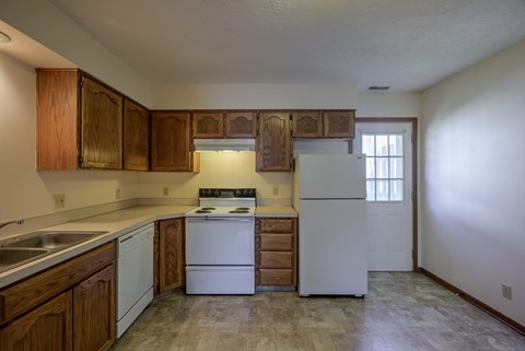 A kitchen with white appliances and wooden cabinets.