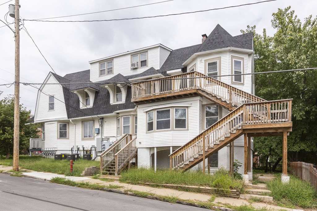 A two-story house with a white exterior and a balcony on the second floor.