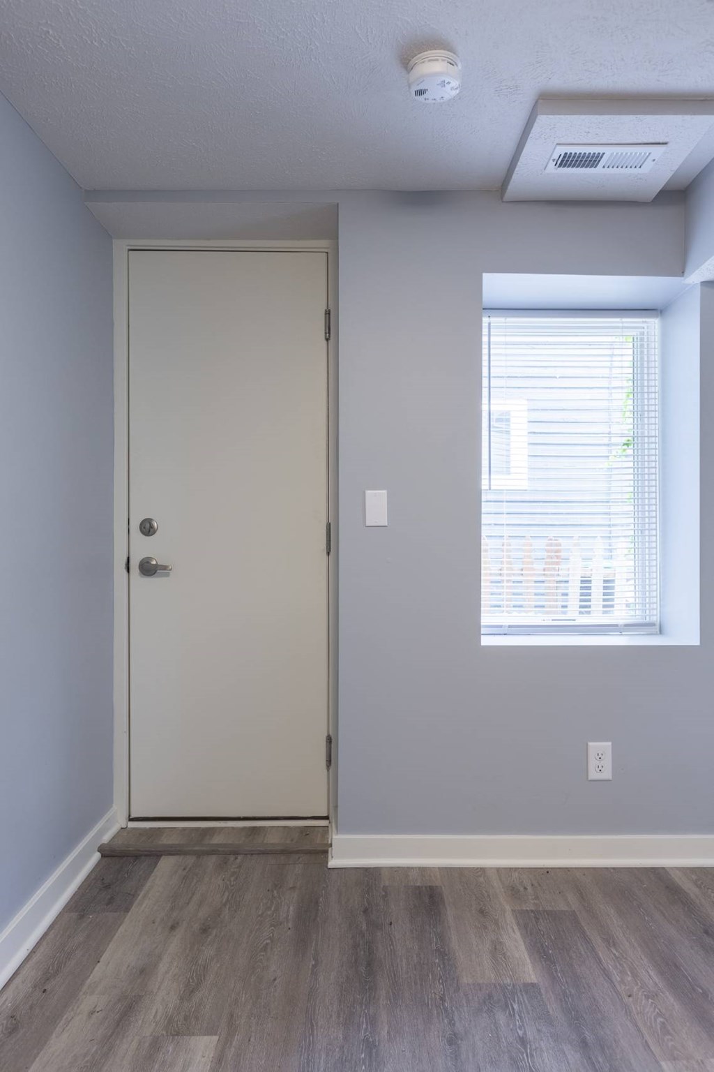 A white door is in a room with a window.
