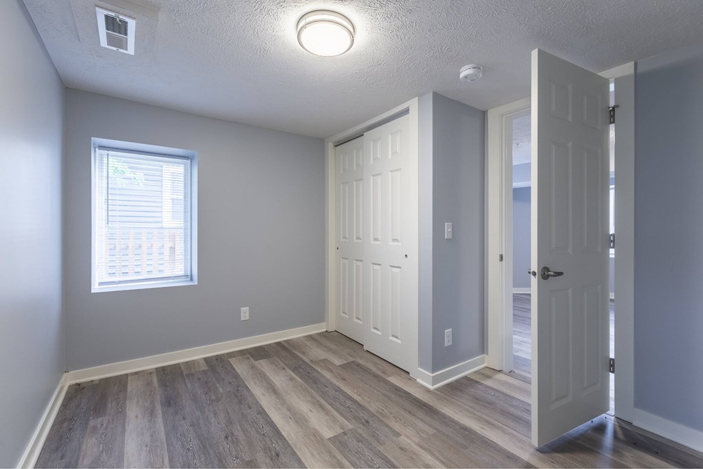 A room with a window and a wooden floor.