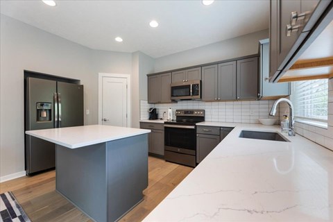 A modern kitchen with a white countertop and dark brown cabinets.